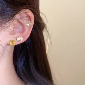 Vue détaillée de boucles d'oreilles en cristal rond brillant sur l'oreille d'une femme asiatique.