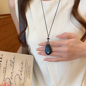 Detailopname van een retro ketting met zwarte druppelhanger en leren koord