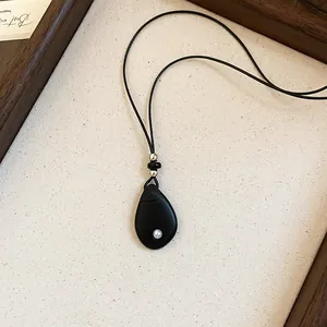 Gedetailleerde weergave van de minimalistische zwarte druppelhanger met zwart koord