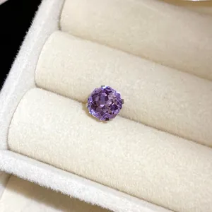 Gros plan d'une boucle d'oreille en pierre violette facettée dans un écrin à bijoux.
