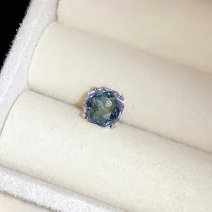 Détail d'une boucle d'oreille en cristal à facettes changeant de couleur dans un écrin.