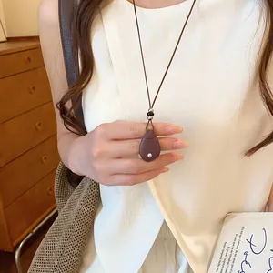 Detailopname van een vintage ketting met druppelhanger en leren koord bij een model