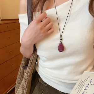 Close-up van een vintage donkerrode ketting met waterdruppel hanger op een model