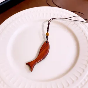 Detail van vintage houten vis hanger met natuurlijke nerf op een stijlvolle ketting.