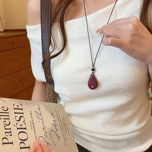 Detailweergave van een vintage donkerrode druppelhanger ketting aan een leren koord
