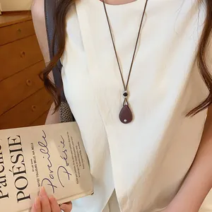 Detail van een vintage leren koord ketting met een minimalistische druppelvormige hanger.