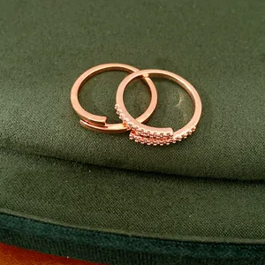Gros plan détaillé d'une bague ouverte en or rose et zircon sur coussin en velours.