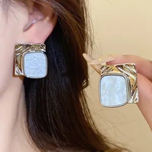 Detailed view of silver-tone pleated square earrings with white marble inlay