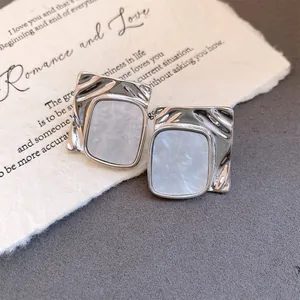 Detail shot of silver wrinkled square earrings with white marble acetate inlay