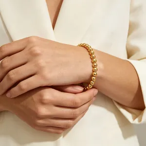 Detailansicht eines 18K vergoldeten 6mm Perlenarmbands an einem Handgelenk.