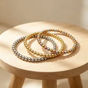 Set aus drei minimalistischen 6-mm-Edelstahl-Perlenarmbändern auf einem Holzhocker.
