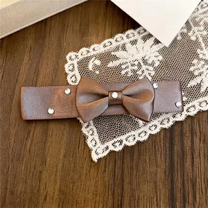 Nahaufnahme einer eleganten braunen Schleifen-Haarspange mit funkelnden Strass-Akzenten.