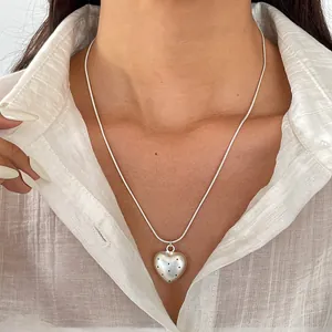 Primo piano di una collana con ciondolo a cuore argento e raffinato motivo a pois neri
