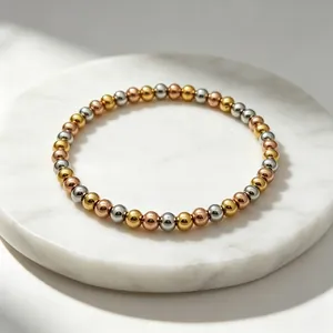 Nahaufnahme eines 6 mm dicken dreifarbigen Perlenarmbands aus poliertem Edelstahl in Gold und Silber