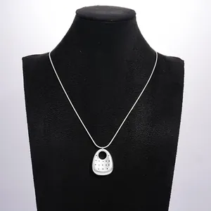 Dettaglio di una collana con pendente ovale in argento e motivo a pois su busto nero