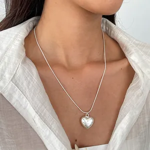 Primo piano di una collana con ciondolo a cuore in argento con pois neri su un collo.