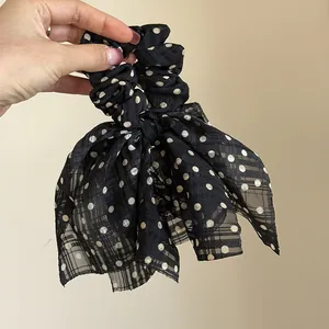 Detailed macro view of black polka dot chiffon bow scrunchie with plaid texture