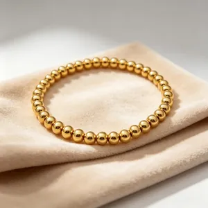 Detailansicht eines 18K vergoldeten Edelstahl-6mm-Perlenarmbands auf Samtbeutel
