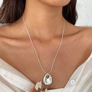Dettaglio macro di una collana con ciondolo ovale traforato in argento e pois neri