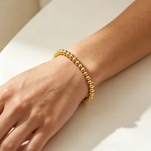 Nahaufnahme eines 6mm 18K vergoldeten Perlenarmbandes am Handgelenk mit minimalistischem Design.