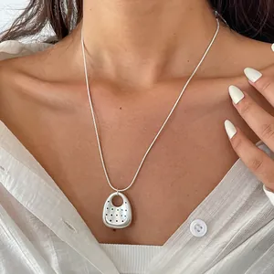 Primo piano di una collana minimalista in argento con pendente ovale su una modella