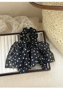 Close-up detail of a black and white polka dot chiffon bow scrunchie on a display