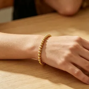 Elegantes 6mm 18K vergoldetes Edelstahl Perlenarmband am Handgelenk einer Frau gezeigt