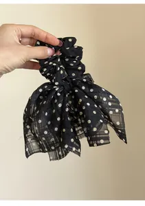 Close-up detail of a black chiffon bow scrunchie with white polka dot pattern design