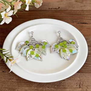 Forest style earrings with cat's eye beads and iridescent acrylic petals on a plate.