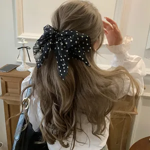 Chiffon polka dot bow hair tie shown as a back-of-head accessory on wavy hair