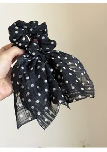 Detailed macro view of the black polka dot chiffon fabric on this bow scrunchie accessory.