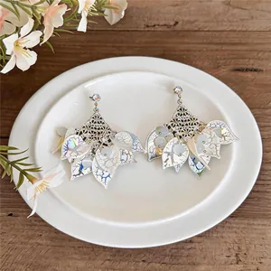 Close-up of forest style earrings with acrylic petals and cat-eye stones on a white plate