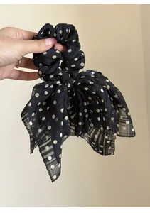 Close-up of black chiffon bow scrunchie with white polka dots for elegant hair styling