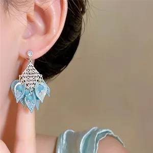 Close-up of elegant forest-style earrings with blue acrylic petals and beads