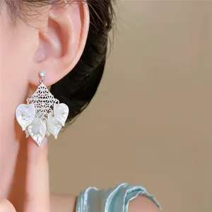 Close-up detail of forest style earrings with acrylic petals and cat-eye stones on model