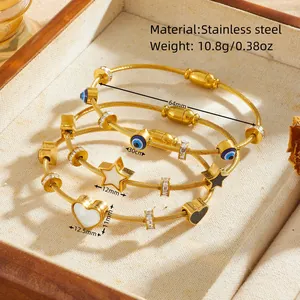 Vista dettagliata di bracciali in acciaio dorato con ciondoli malocchio, cuore e stella.