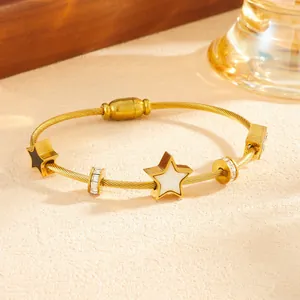 Dettaglio di un bracciale in acciaio al titanio dorato con ciondoli a stella e cristalli