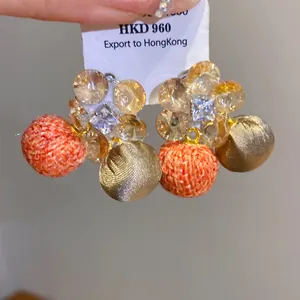 Detailopname van zirkonia bloemenoorbellen met hangers van textiel en satijn.