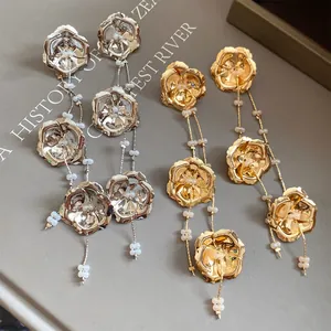 Detaillierte Nahaufnahme eleganter Metall-Rosen-Ohrringe mit Quasten in Gold und Silber
