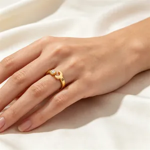 Macro view of a gold-plated wrench-shaped open ring with a small sparkling stone inlay.