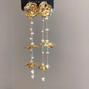 Detailansicht der eleganten goldenen Blumentropfenohrringe mit weißen Glasperlenanhängern