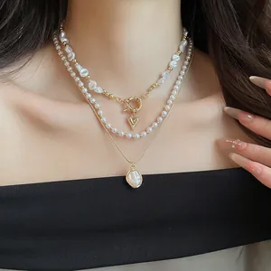 Gedetailleerd zicht op een drielaagse parel- en gouden hartvormige hangerketting.