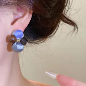 Detailweergave van een multi-materiaal oorknopje met stoffen bal en kralen bij een model