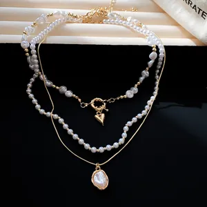 Detailopname van elegante drielaagse parelketting met hart- en schelpachtige hangers