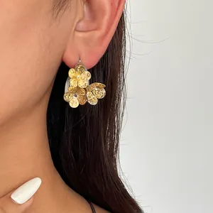 Nahaufnahme von goldenen Vintage-Blumenohrringen mit Textur an einem eleganten Model