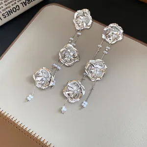 Detailansicht eleganter silberner Metallblumen-Ohrhänger mit Perlenverzierung.
