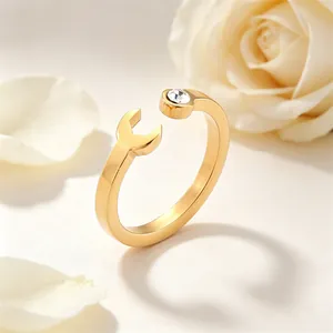 Detailed macro view of a gold-plated wrench-shaped stainless steel ring with crystal.
