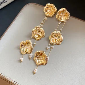 Nahaufnahme von eleganten Gold-Metallblüten-Ohrringen mit weißen Perlen-Quasten