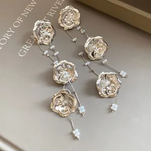 Detailansicht eleganter silberner Metallblumenohrringe mit zarten Glasperlen-Quasten