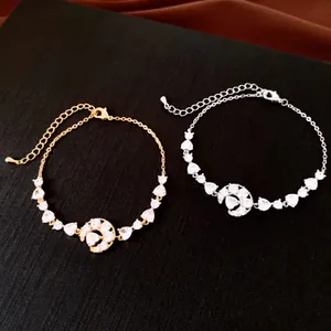 Détail de bracelets lune et cœur en or et argent ornés de pierres de zircone étincelantes.